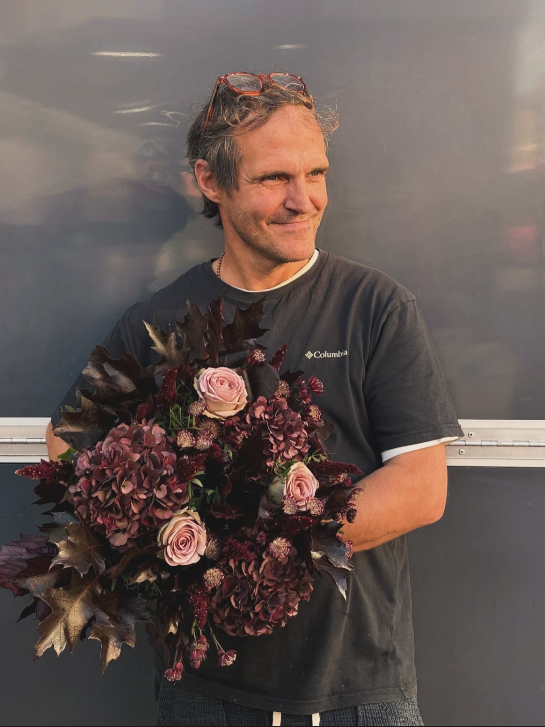 David Shaw holding a bouquet of aubergine foliage and pink roses